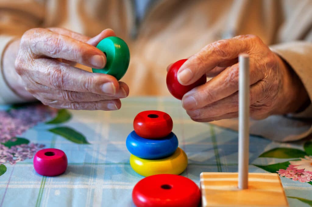 an elderly man playing with toys at a table
