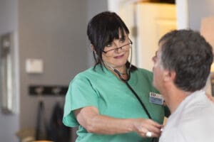 Nurse providing in-home care to elderly patient as part of a home health value based purchasing program